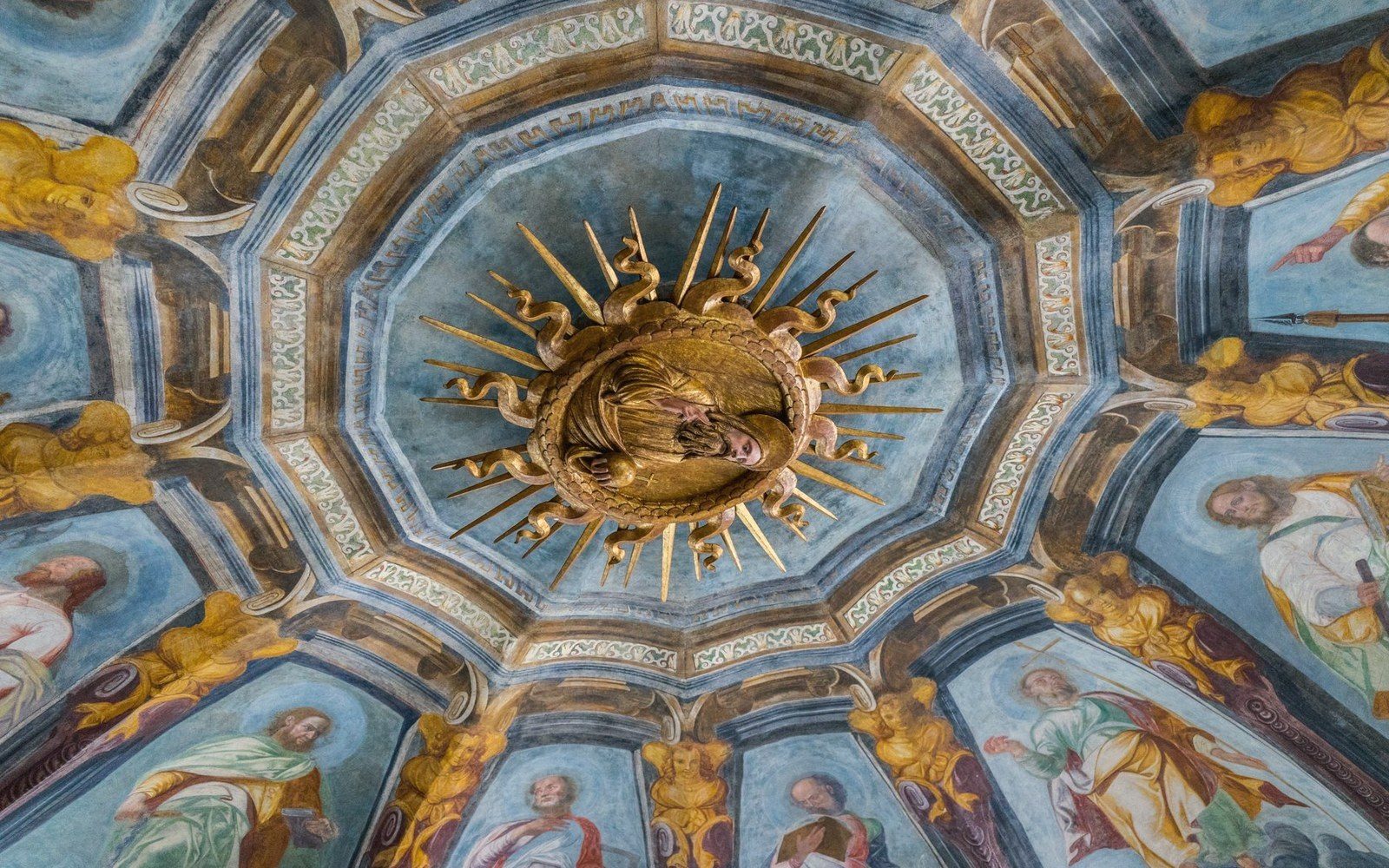 Gilded sunburst medallion at the center of a domed ceiling painted with saints in blue tones