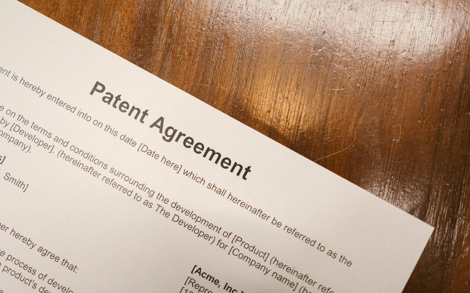 A printed patent agreement document lying on a wooden table