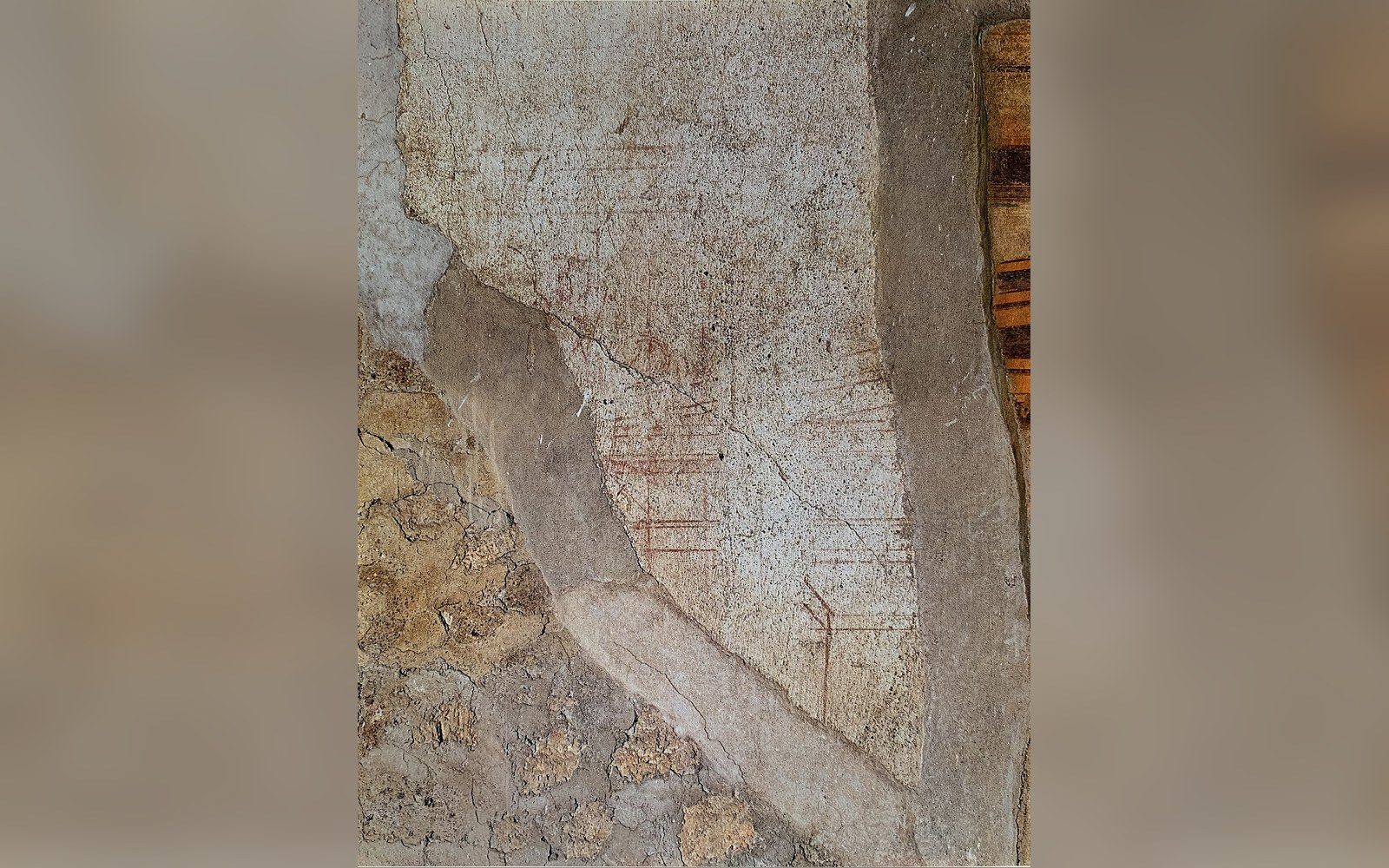 Faint red ochre sinopia underdrawing visible beneath cracked ancient plaster on a wall