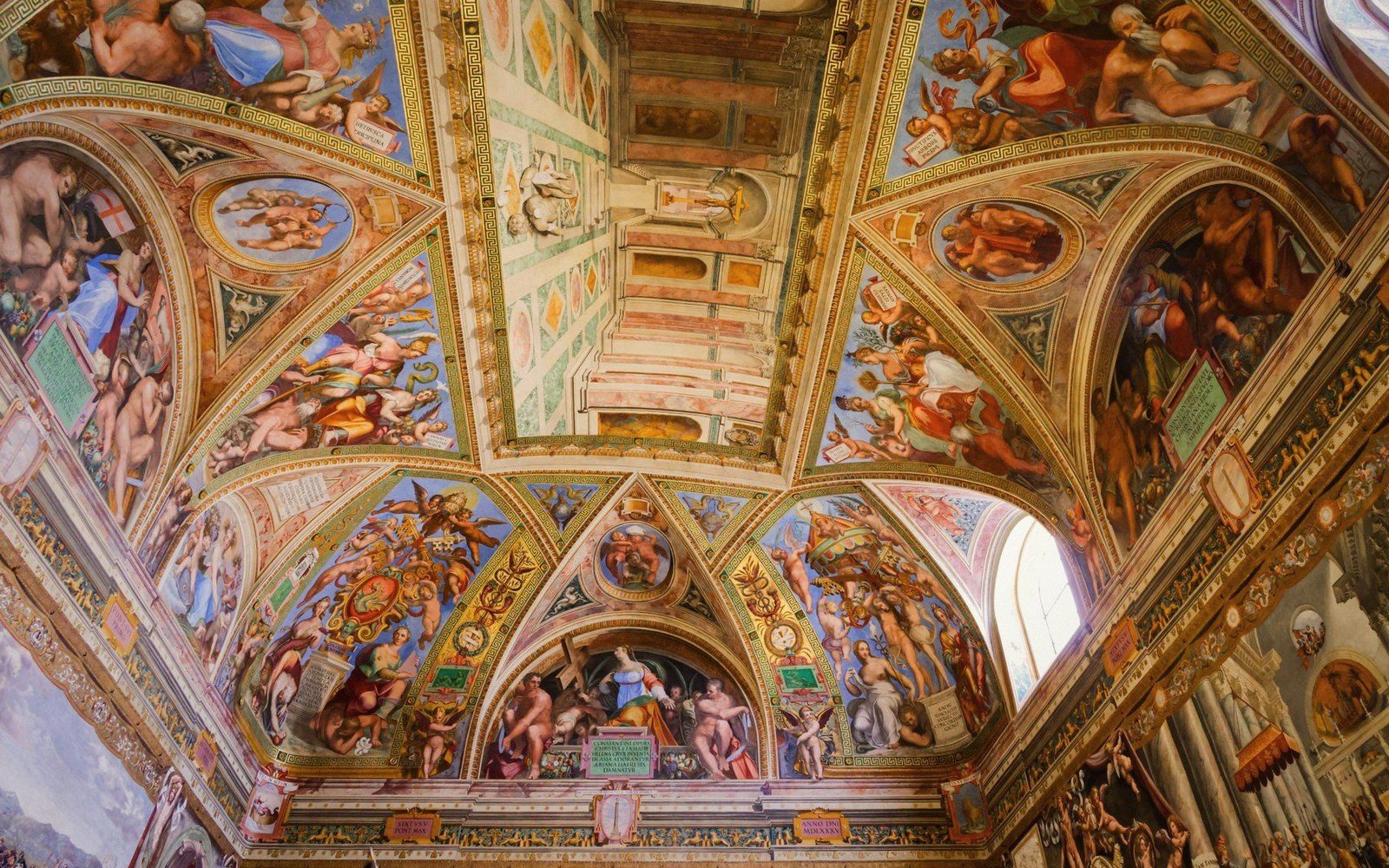 Ornate frescoed vaulted ceiling with religious paintings in gilded arched panels